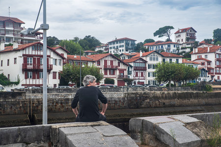 A tourist looks at the town of Saint Jean de Luz in France with its typical architectural housesの写真素材
