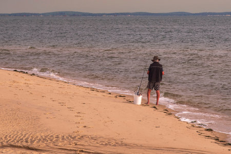 A man fishing at the water's edge on a sandy beachの写真素材