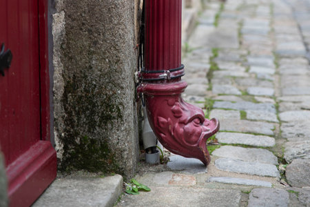Red metal gutter in the shape of an animal's head in the streets of Le Croisic