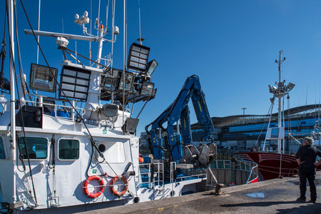 Fishing boat with cranes, lighthouses and fishermen's nets in the seaside port of Santona in Cantabria in Spainの写真素材