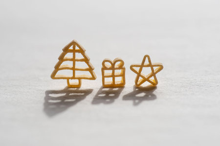 Pasta in the shape of a Christmas tree, gifts, miniature Santa Claus and a star, on a light...