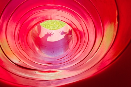 Playing in the red plastic tunnel slideの写真素材