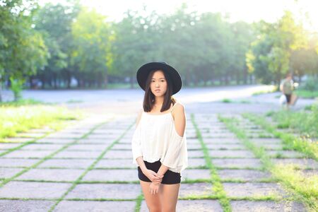 female hat nature summer sun sunset looks pleased. azitka woman black hair dancing around the trees looking at the camera. portrait.の写真素材