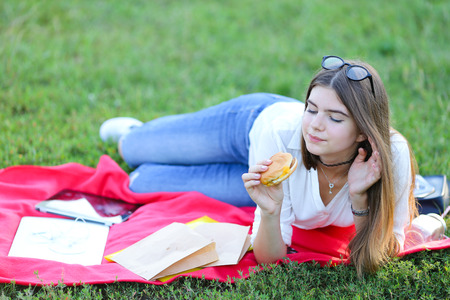 girl lying on the nature and eateth fast food. student working in the park and eat.の写真素材