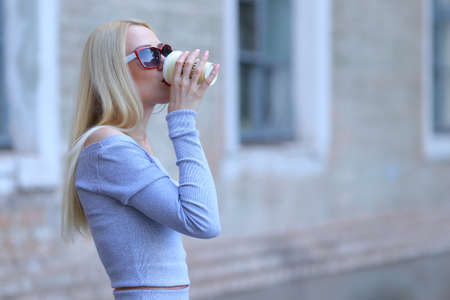Woman blond hair slim athletic figure near brick wall stands wearing sunglasses.の写真素材