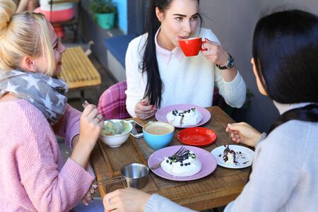 Concept female friendship, meeting, lunch. Three beautiful women sitting incafe smiling, talking,...