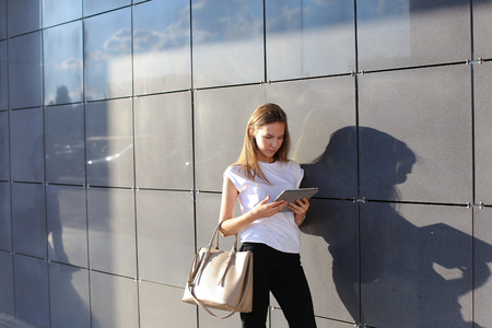 Female work, negotiating, solves problems, browsing touch looking tablet. Young beautiful business woman entrepreneur with long hair wearing suit standing near center technology sun.の写真素材