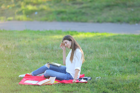 feminine working outdoors with papers in glasses. in the park for a laptop fast food snack and uses a tabletの写真素材