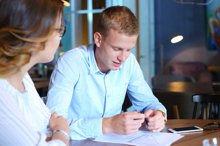 Smart young business men one woman suits sitting on table documents, graphics, technology,  Leaf catalog pages. Team entrepreneurs negotiate, discuss issues, solve problems, agree, talkの写真素材