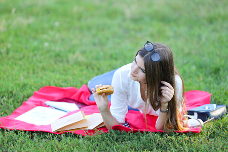 girl lying on the nature and eateth fast food. student working in the park and eat.の写真素材