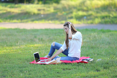 feminine working outdoors with papers in glasses. in the park for a laptop fast food snack.の写真素材