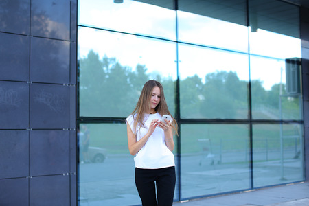 Young beautiful business woman entrepreneur with long hair wearing a suit standing near center business technology. Female work, negotiating, solves problems, dials, talking on smart phoneの写真素材