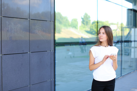 Young beautiful business woman entrepreneur with long hair wearing a suit standing near center business technology. Female work, negotiating, solves problems, dials, talking on smart phoneの写真素材