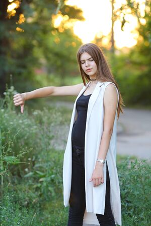 Woman with long hair and beautiful eyes on a green background shows the different human emotions. Lady portrays unworthy, not likeの写真素材