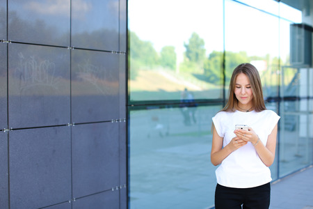 Young beautiful business woman entrepreneur with long hair wearing a suit standing near center business technology. Female work, negotiating, solves problems, dials, talking on smart phoneの写真素材