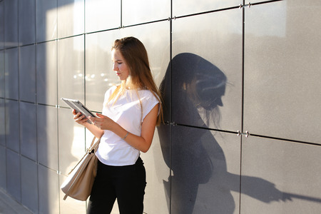 Female work, negotiating, solves problems, browsing touch looking tablet. Young beautiful business woman entrepreneur with long hair wearing suit standing near center technology sun.の写真素材