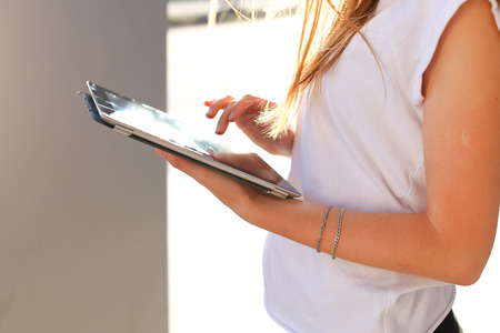 Female work, negotiating, solves problems, browsing touch looking tablet. Young beautiful business woman entrepreneur with long hair wearing suit standing near center technology sun.の写真素材