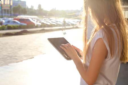 Female work, negotiating, solves problems, browsing touch looking tablet. Young beautiful business woman entrepreneur with long hair wearing suit standing near center technology sun.の写真素材