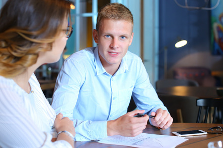 Smart young business men one woman suits sitting on table documents, graphics, technology,  Leaf catalog pages. Team entrepreneurs negotiate, discuss issues, solve problems, agree, talkの写真素材