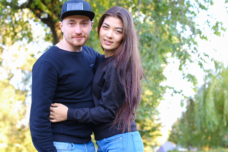 Happy couple of young beautiful people embrace and lead dialogue among themselves, laughing and making plans for future, planning wedding and discuss relationship, firmly hold hands and look forward to meeting with friends. Young people stand in beautifulの写真素材