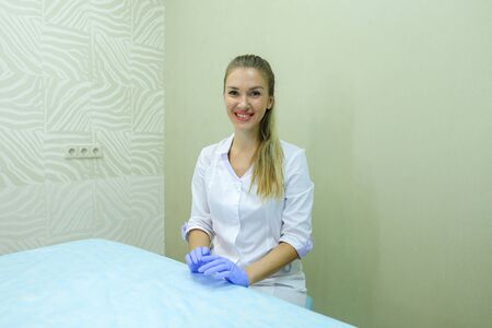 Cute female master of bio tattooing eyebrows, preparing for start of working day, disinfects and selects tools with which to work, changes or putting on gloves, advertises beauty salon or advertising professional tools for permanent makeup, conducts masteの写真素材