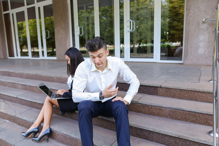Young contemporary confident people, perspective entrepreneurs, students smiling, chatting with each other, using gadgets, laptops for work with office programs, drawing up business plan, discuss working moments, share of business ideas, solve problems, sの写真素材