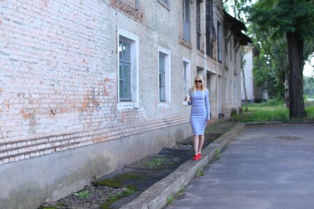 Woman blond hair slim athletic figure near brick wall stands wearing sunglasses.の写真素材