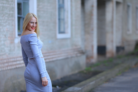 Handsome Beautiful female girl lady hug. Woman blond hair slim athletic figure near brick wall stands wearing red lips.の写真素材