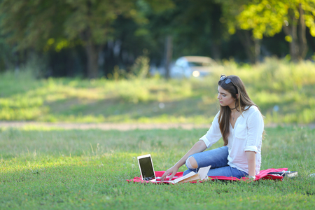 feminine working outdoors with papers in glasses. in the park for a laptop fast food snack.の写真素材