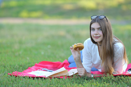 girl lying on the nature and eateth fast food. student working in the park and eat.の写真素材