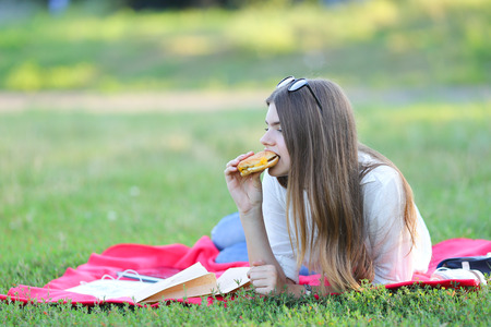 girl lying on the nature and eateth fast food. student working in the park and eat.の写真素材