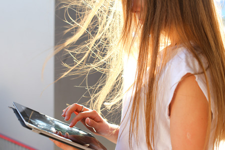 Female work, negotiating, solves problems, browsing touch looking tablet. Young beautiful business woman entrepreneur with long hair wearing suit standing near center technology sun.の写真素材