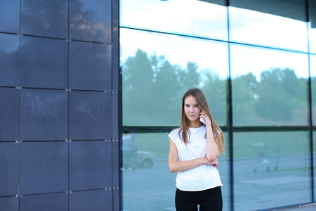 Young beautiful business woman entrepreneur with long hair wearing a suit standing near center business technology. Female work, negotiating, solves problems, dials, talking on smart phoneの写真素材