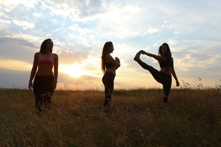 Women perform warm-up and stretching exercises, strengthen body, exercise classes and share knowledge with each other, take pictures to capture advertising sportswear or fitness center. Girl with shoulder-length hair dressed in pink top and black leggingsの写真素材