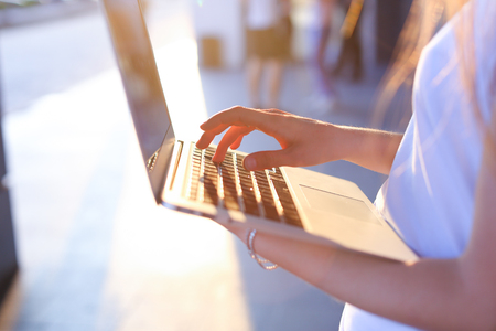 Hand lady press tauchpad keyboard on laptop. Young beautiful female business woman entrepreneur long hair wearing suit standing near center technology sunの写真素材