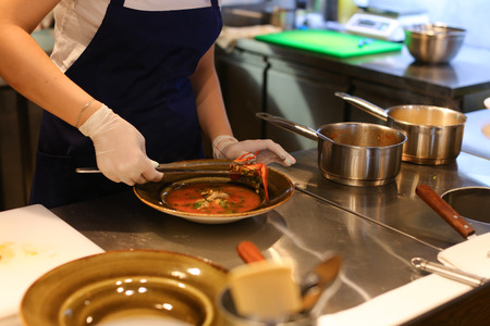 Girl female woman chef prepares dishes in the restaurant, pours into a bowl, gloved hands, a kitchen for cookingの写真素材