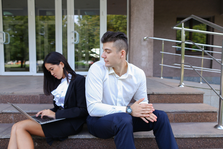 Young contemporary confident people, perspective entrepreneurs, students smiling, chatting with each other, using gadgets, laptops for work with office programs, drawing up business plan, discuss working moments, share of business ideas, solve problems, sの写真素材