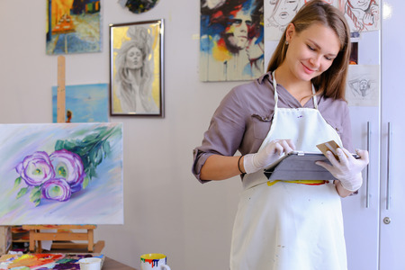 Beautiful Female Painter Orders Through Internet or Picture Frames With Supplies, Clarifies Meeting With Students For Master Class, Communicates With Clients About Sale of Paintings. Woman With Long Light Brown Hair Dressed Sht Pale Purple Jacket, White Aの写真素材