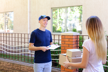 Courier Man Delivered Box to Woman to Home , Ranner Gives Pen and Documents, Girl Signs and Takes Boxes. International Manufacturer of Medical Materials Provides Courier For Purchases, Messenger For You, Courier Man of European Appearance Provides Pen andの写真素材