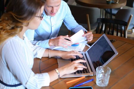 Smart young business men one woman suits sitting on table documents, graphics, technology,  Leaf catalog pages. Team entrepreneurs negotiate, discuss issues, solve problems, agree, talkの写真素材