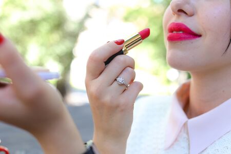 makeup Concept. Girl paints a big red lipstick in cafeの写真素材