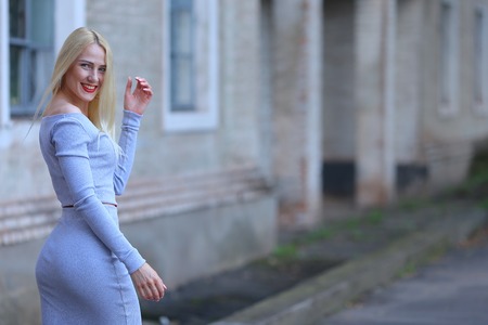 Handsome Beautiful female girl lady hug and kiss. Woman blond hair slim athletic figure near brick wall stands wearing red lips.の写真素材