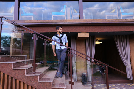 Bearded Arab man, businessman students gathered to spend time at restaurant and decided to have dinner, arranged business meeting with colleagues and waits at entrance to restaurant, smiling and enjoying life, posing for catalog of brand of mens clothing.の写真素材