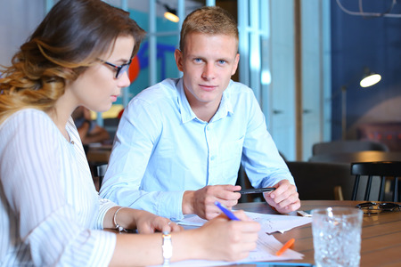 Smart young business men one woman suits sitting on table documents, graphics, technology,  Leaf catalog pages. Team entrepreneurs negotiate, discuss issues, solve problems, agree, talkの写真素材