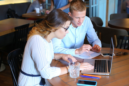 Smart young business men one woman suits sitting on table documents, graphics, technology,  Leaf catalog pages. Team entrepreneurs negotiate, discuss issues, solve problems, agree, talkの写真素材