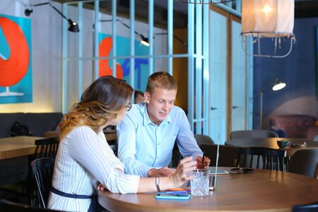 Smart young business men one woman suits sitting on table documents, graphics, technology,  Leaf catalog pages. Team entrepreneurs negotiate, discuss issues, solve problems, agree, talkの写真素材