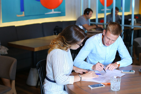 Smart young business men one woman suits sitting on table documents, graphics, technology,  Leaf catalog pages. Team entrepreneurs negotiate, discuss issues, solve problems, agree, talkの写真素材