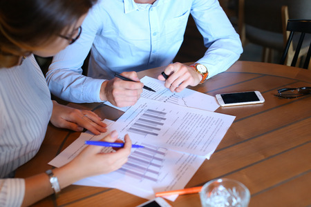 Smart young business men one woman suits sitting on table documents, graphics, technology,  Leaf catalog pages. Team entrepreneurs negotiate, discuss issues, solve problems, agree, talkの写真素材