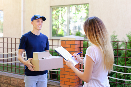 Courier Man Delivered Box to Woman to Home , Ranner Gives Pen and Documents, Girl Signs and Takes Boxes. International Manufacturer of Medical Materials Provides Courier For Purchases, Messenger For You, Courier Man of European Appearance Provides Pen andの写真素材