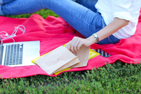 feminine working outdoors with papers in glasses. in the park for a laptop fast food snack and uses a tabletの写真素材